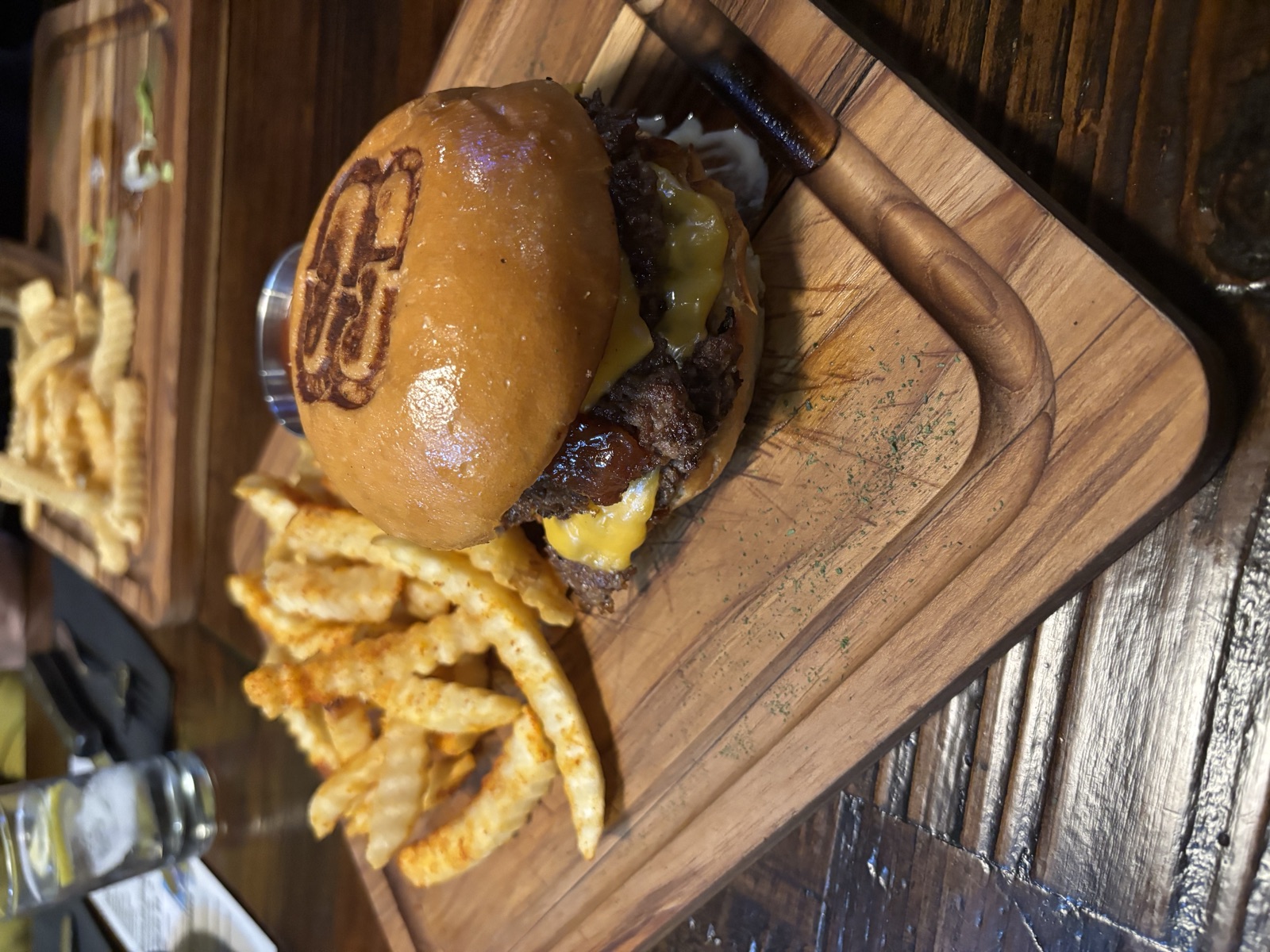 Branded burger and seasoned crinkle fries on the board