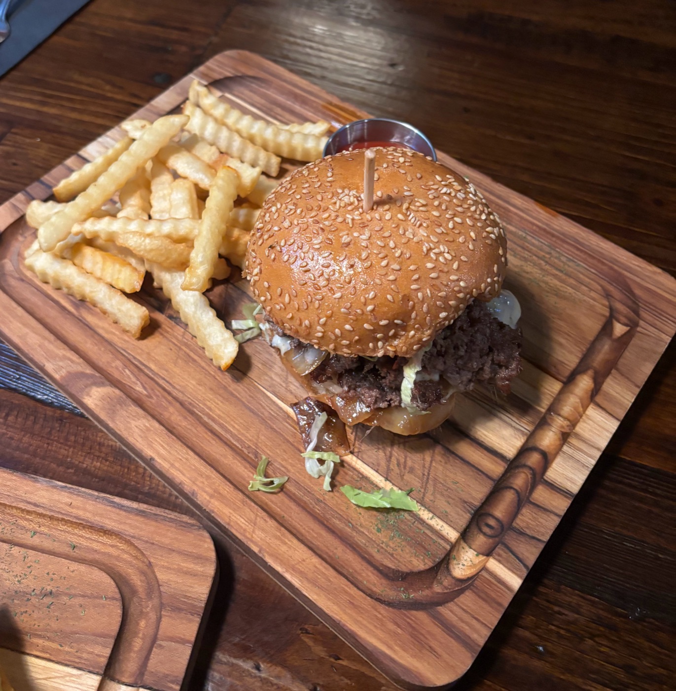 Sesame bun burger with fries on a wood board